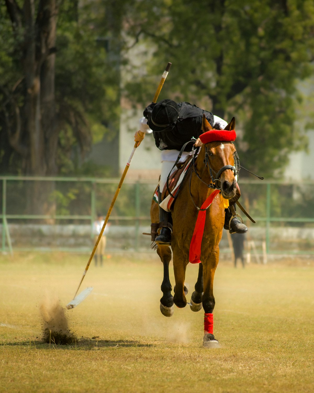 A polo player leaning out of the saddle to hit the ball
