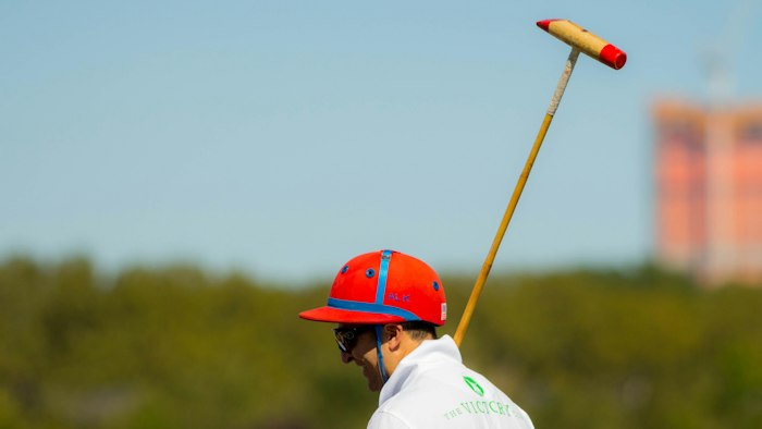 A player in a red helmet holding a polo mallet up